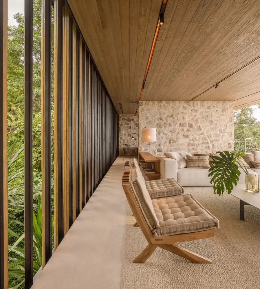 Modern living room with wooden furniture, concrete flooring, and stone accents.