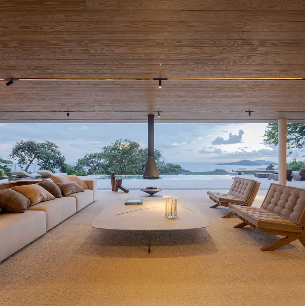 A modern living room featuring minimalist furniture, a wooden floor, and a view of the outdoors.
