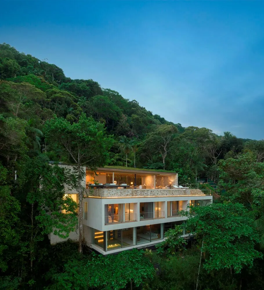 Modern residential home built into the side of a mountain, featuring glass, stone, and wood materials.