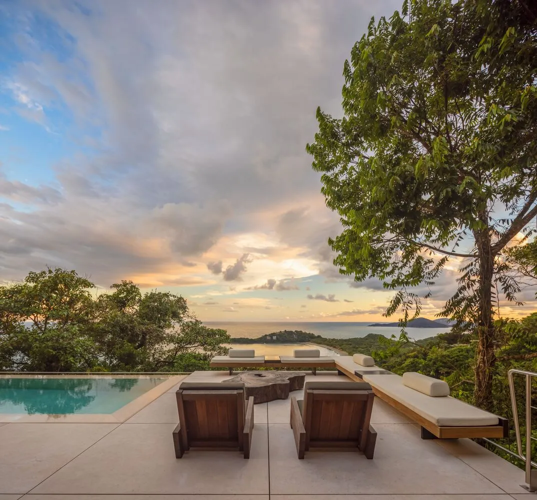 Modern patio with concrete swimming pool, lounge chairs, and scenic ocean view.