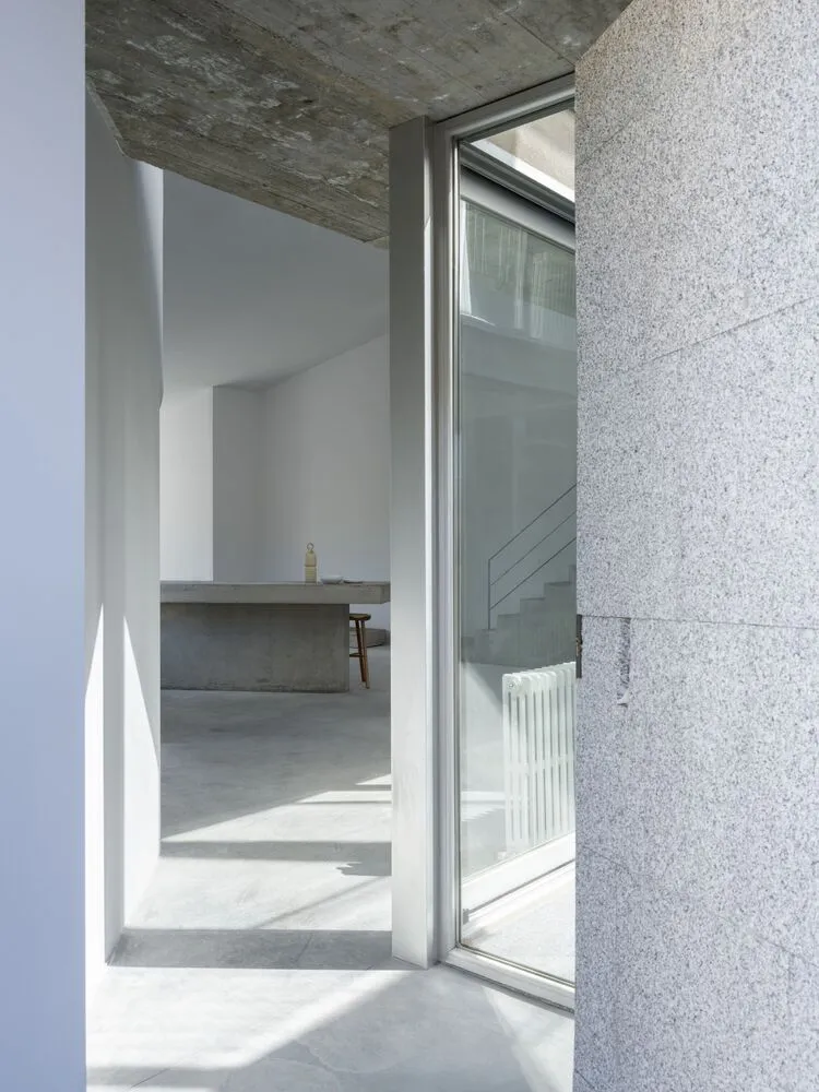 Interior space with modern design elements, including concrete walls, glass doors, and minimalistic furniture.