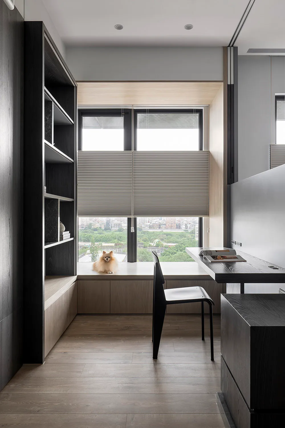 A modern home office featuring a wooden desk with a view of the cityscape outside the window.