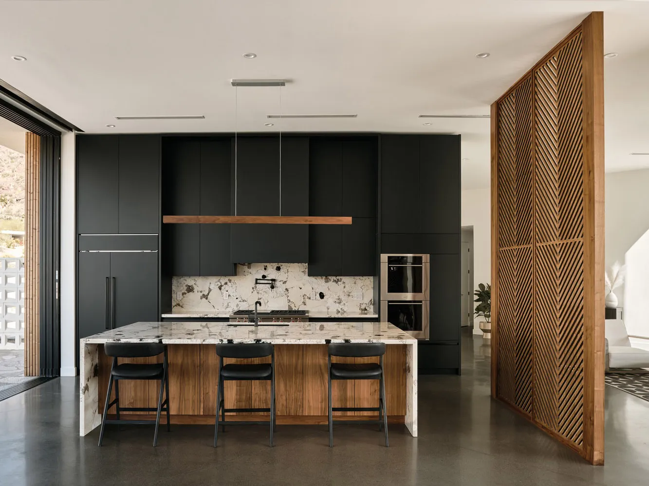 A modern residential kitchen with black wood cabinets and a marble countertop.