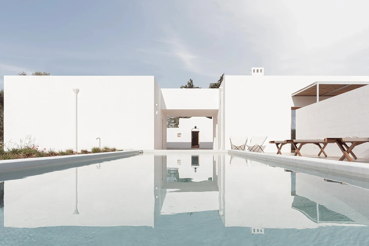 Modern white cube house with concrete exterior and reflecting pool.