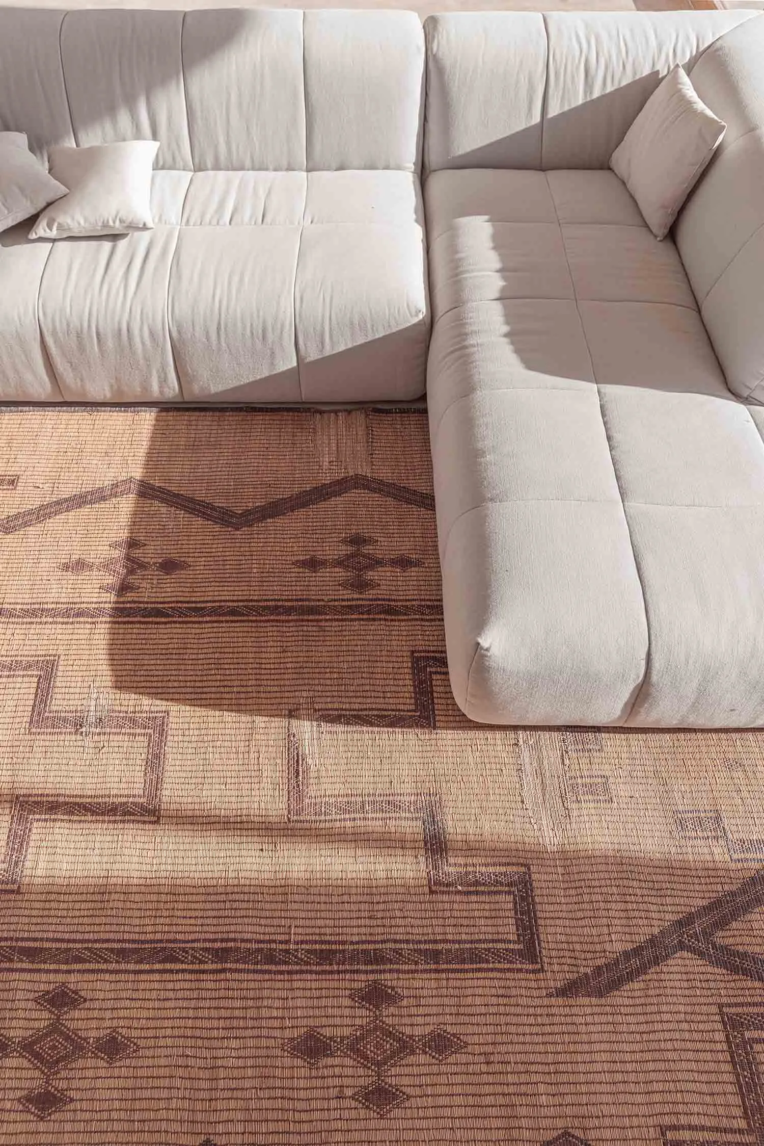 A modern white sofa with a tiled pattern floor rug in a contemporary living room setting.
