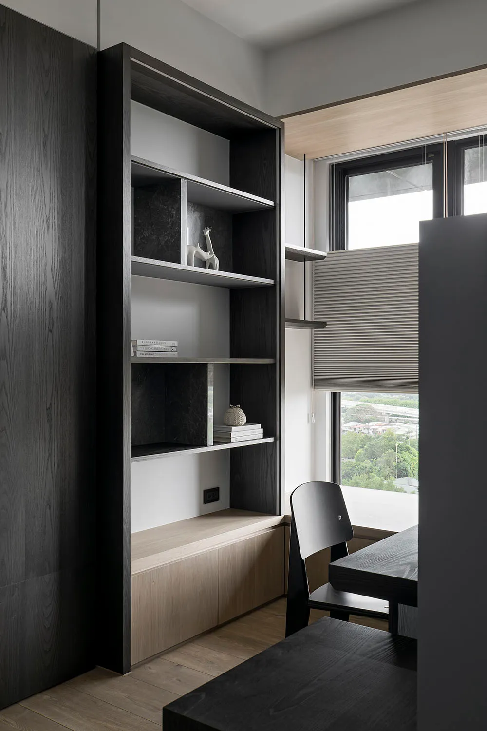 A modern minimalist workspace featuring dark wood furniture and shelves.