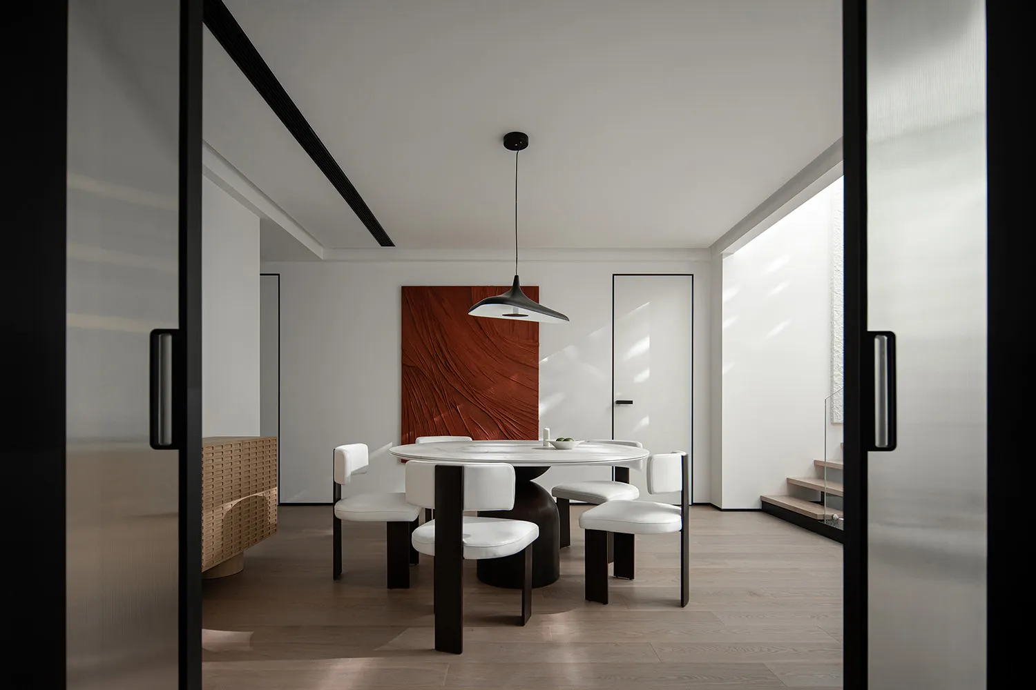 Modern dining room with metal table, white leather chairs, and minimalist decor.