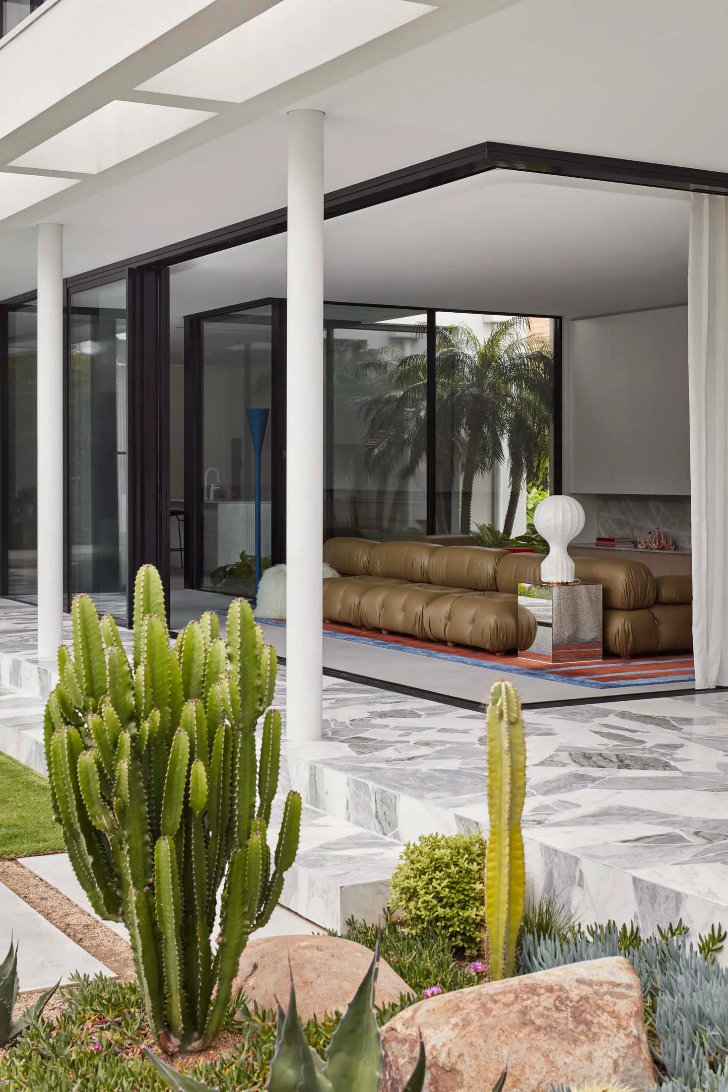 Modern living room with concrete floor, glass walls, and marble accents.