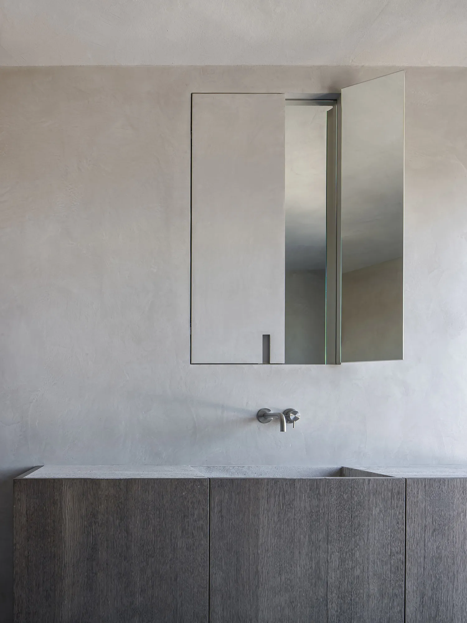 Modern minimalist bathroom featuring a concrete countertop and wooden cabinetry.