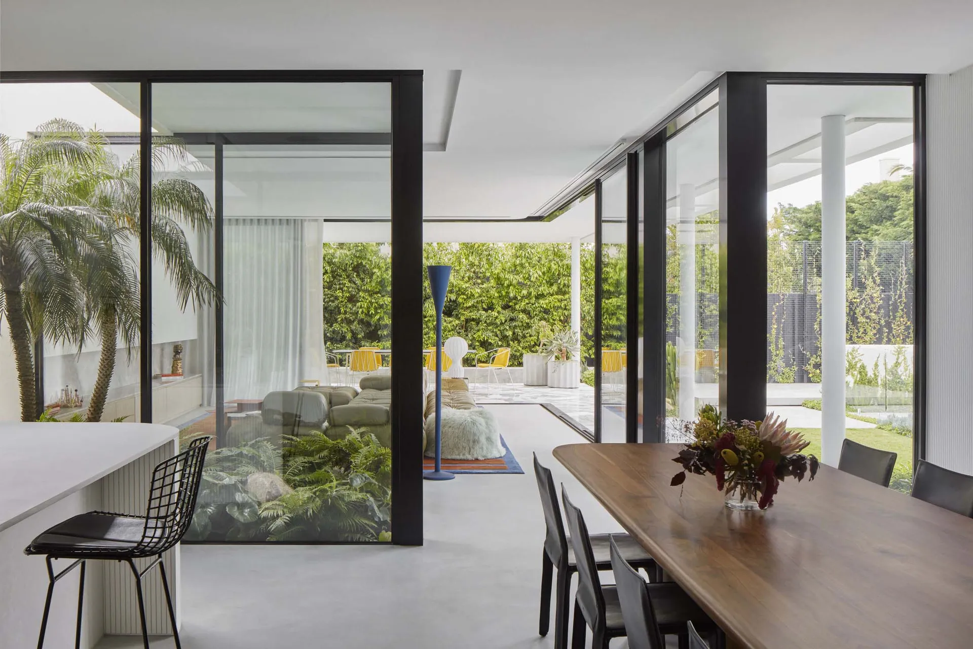 A minimalist living room with glass walls and concrete floor, showcasing sleek design and natural light.