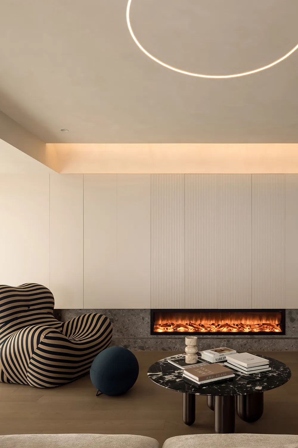 A modern minimalist living room featuring a marble fireplace and coffee table with books and decorative items.