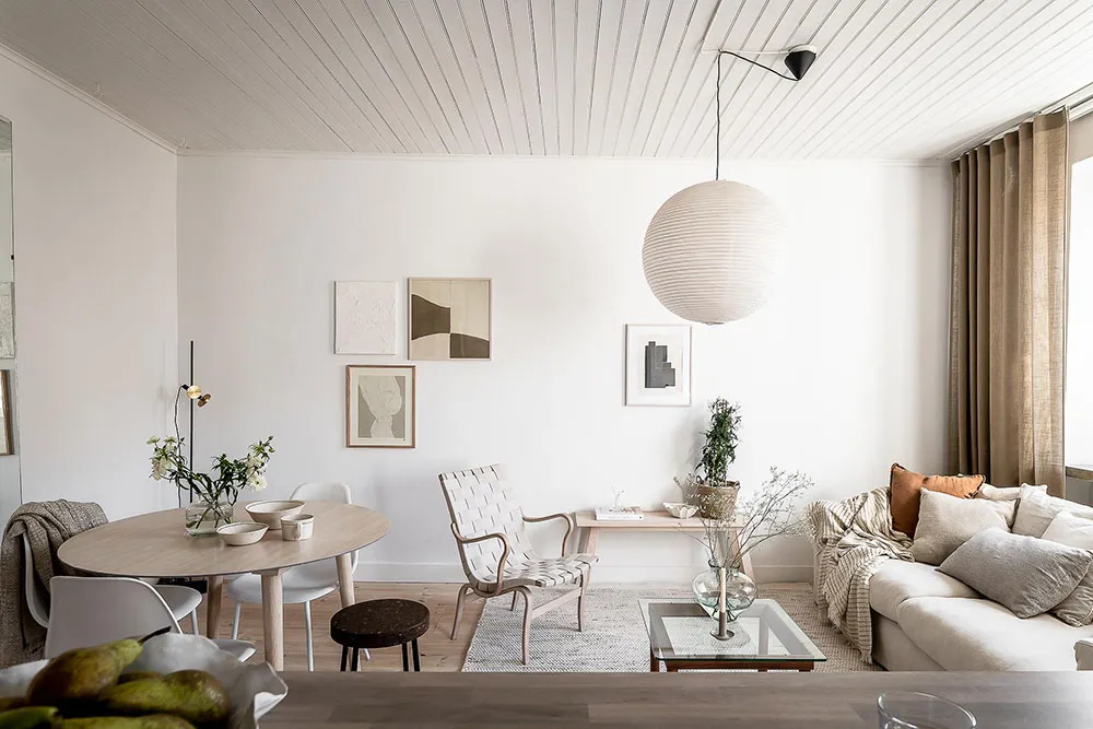 A contemporary living room with minimalist design, featuring timber furniture, a fabric sofa, and a glass coffee table.