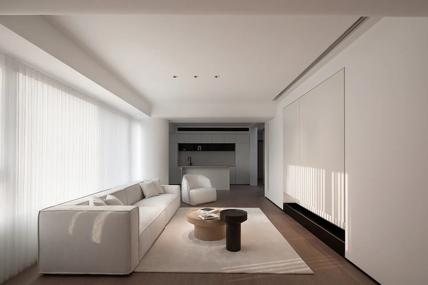 A minimalist living room with white furniture, featuring a comfortable sofa, a coffee table, and a sleek, modern design.