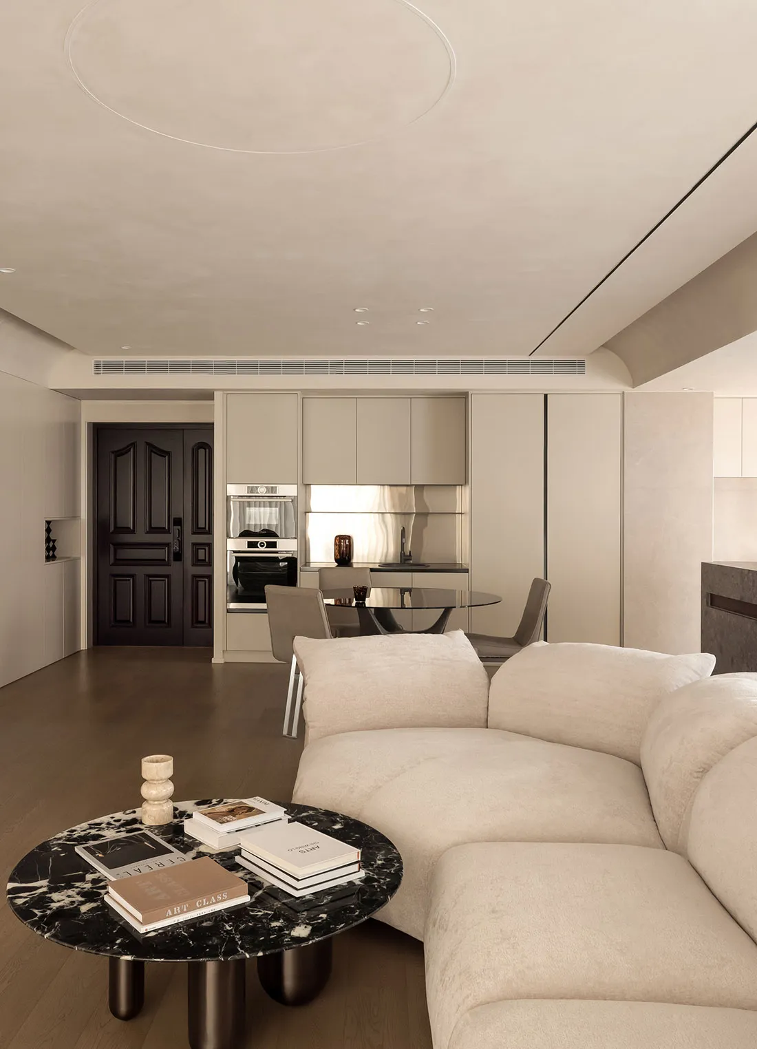 A modern residential interior with a minimalist design, featuring neutral tones and a neutral-colored sectional sofa.
