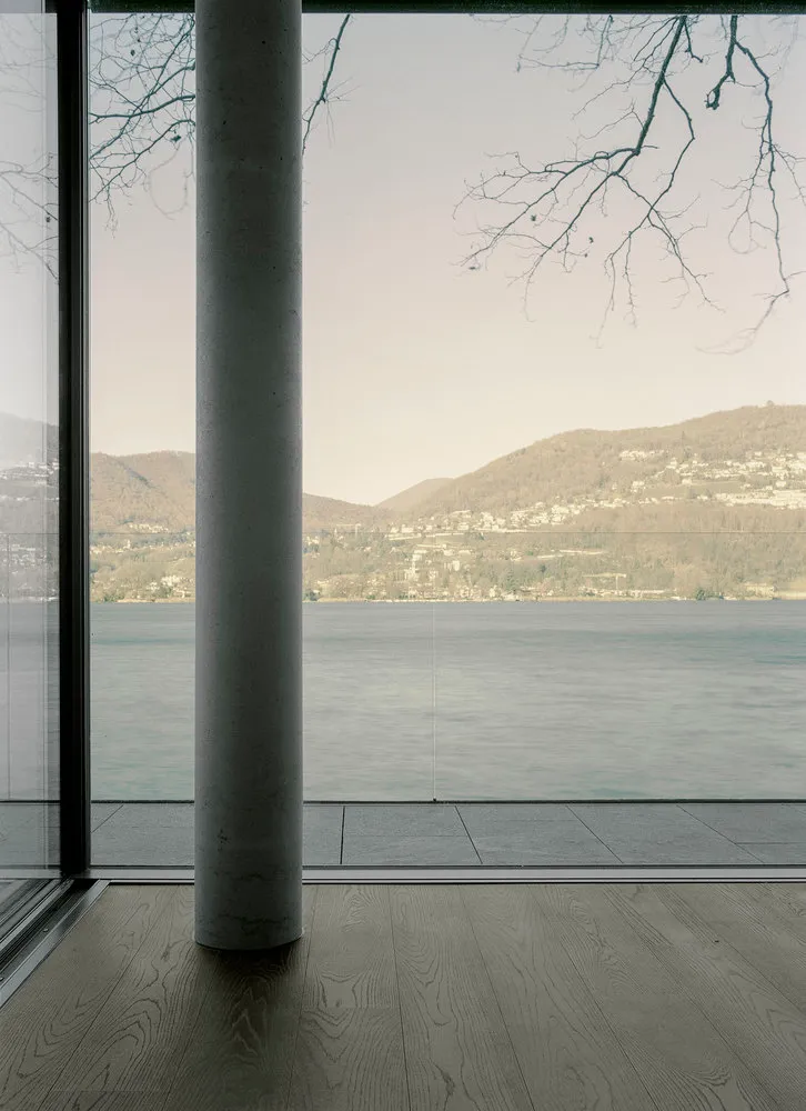 Modern architectural view featuring glass walls, concrete flooring, and a scenic landscape.