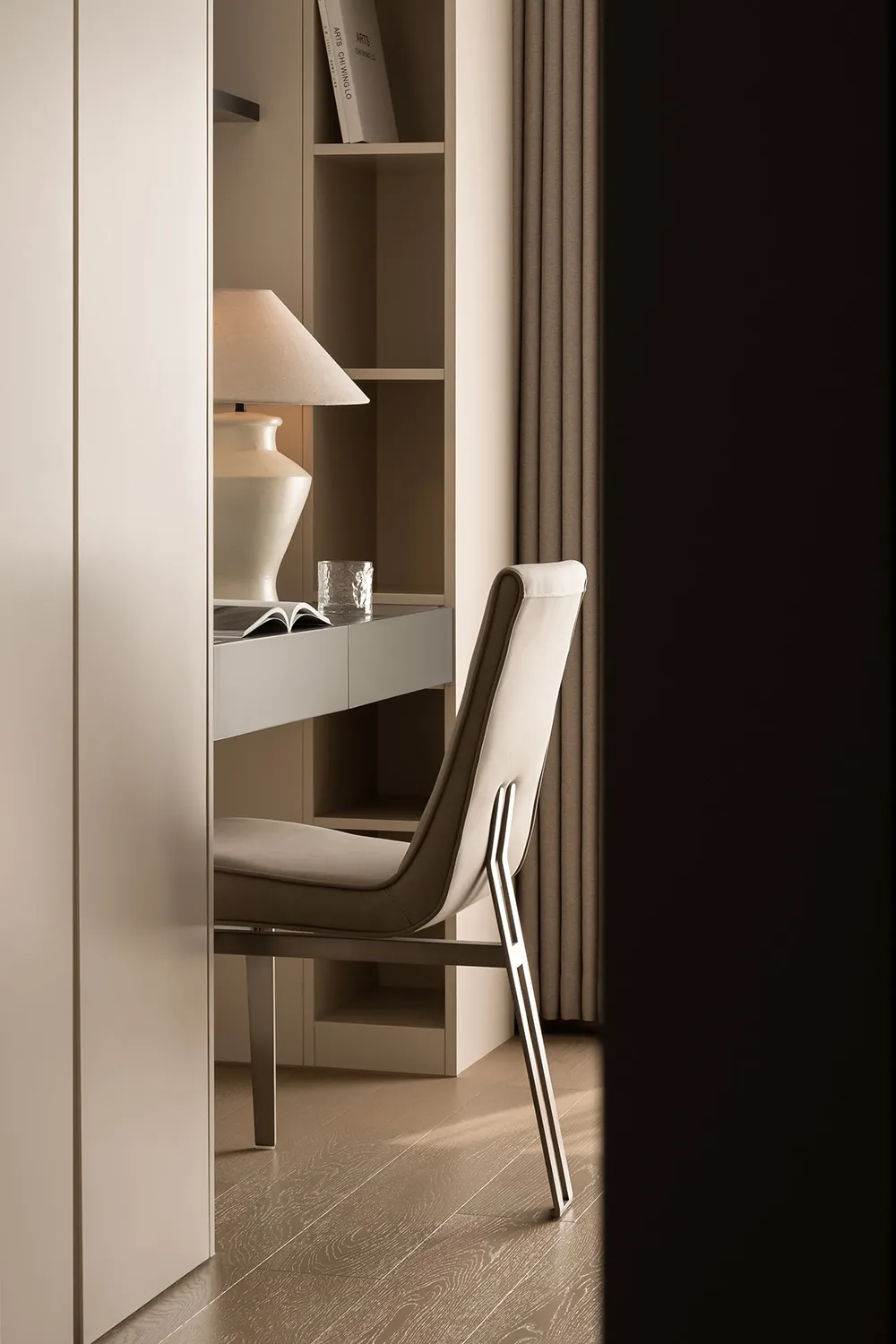 A minimalist home office with white furniture and a beige lamp on a white desk.