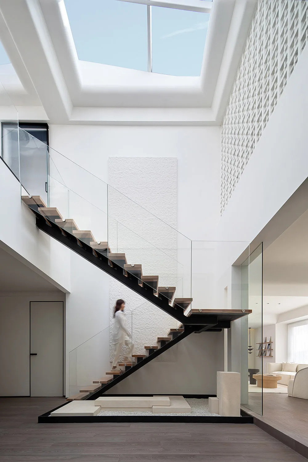 A minimalist interior with a glass staircase, featuring modern design elements like wood, concrete, and an open ceiling.