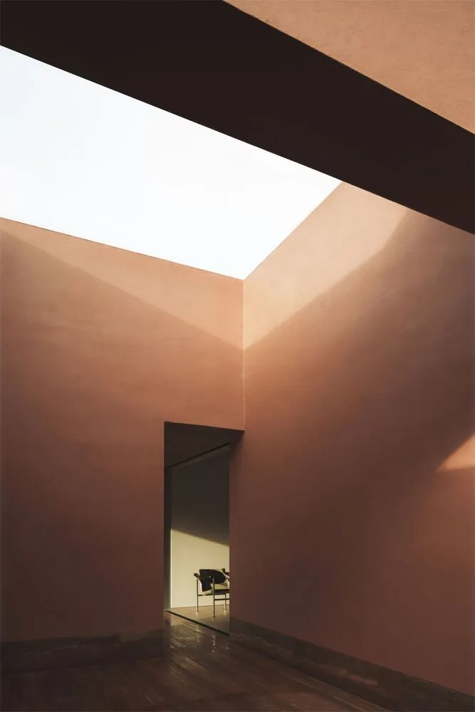 A minimalist space featuring concrete walls and glass ceiling.