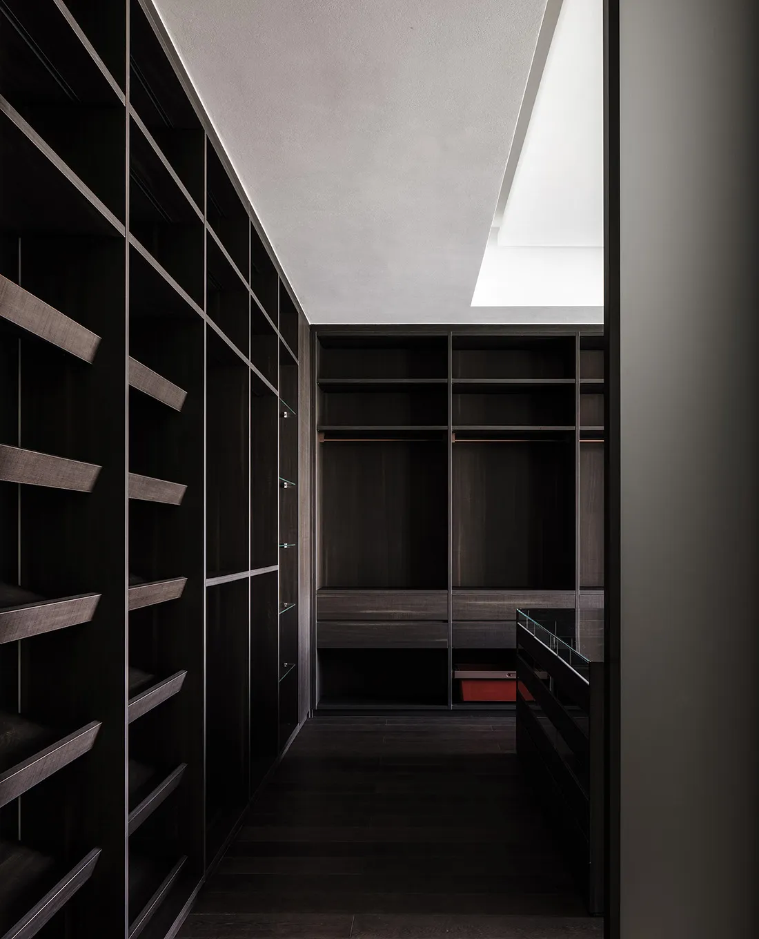 A minimalist dark wood closet with shelves, drawers, and skylights.