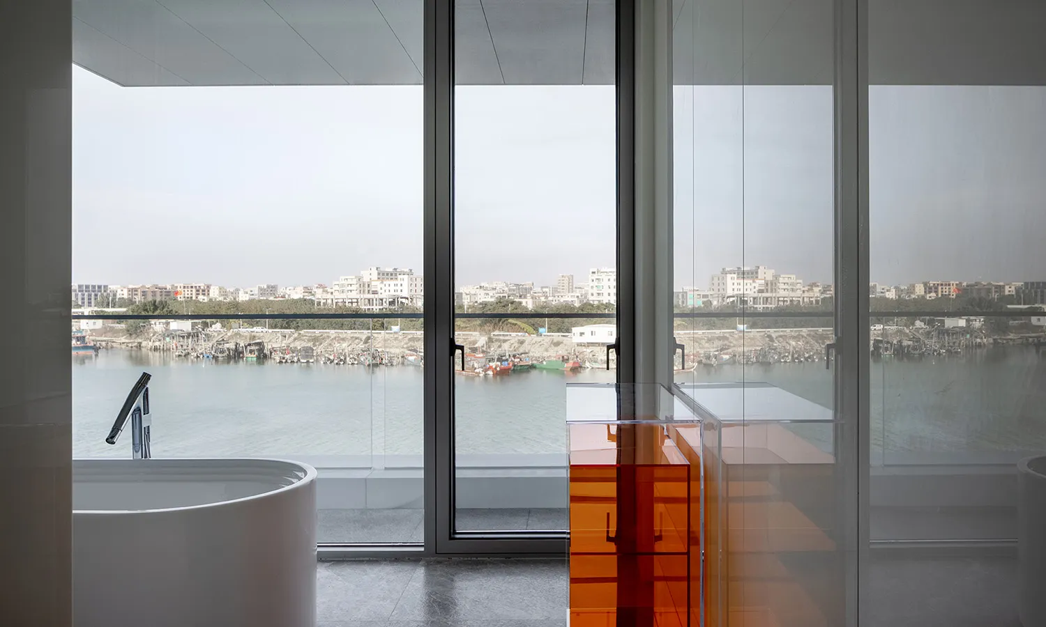 A modern bathroom featuring glass walls and a view of the city through large windows.