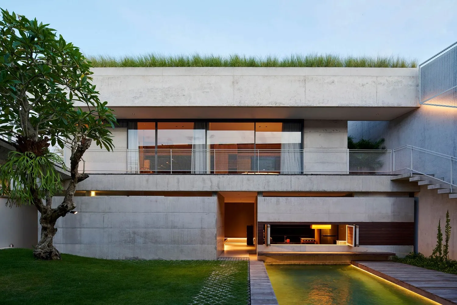 A modern residential building with a concrete exterior, glass windows, and a rooftop garden.