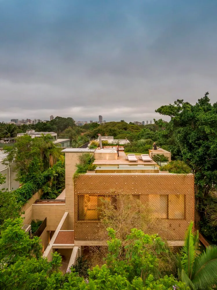 An elevated view of a modern house with a wooden exterior surrounded by lush greenery.