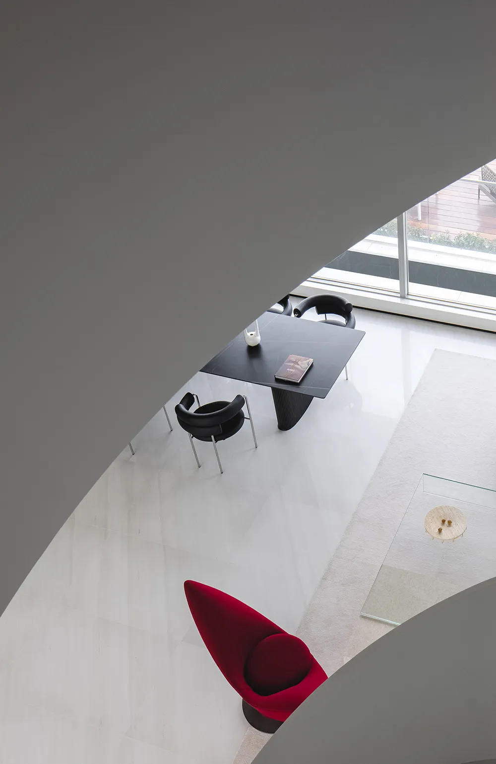A modern living room with a marble floor plan, featuring sleek black furniture and a striking red armchair.