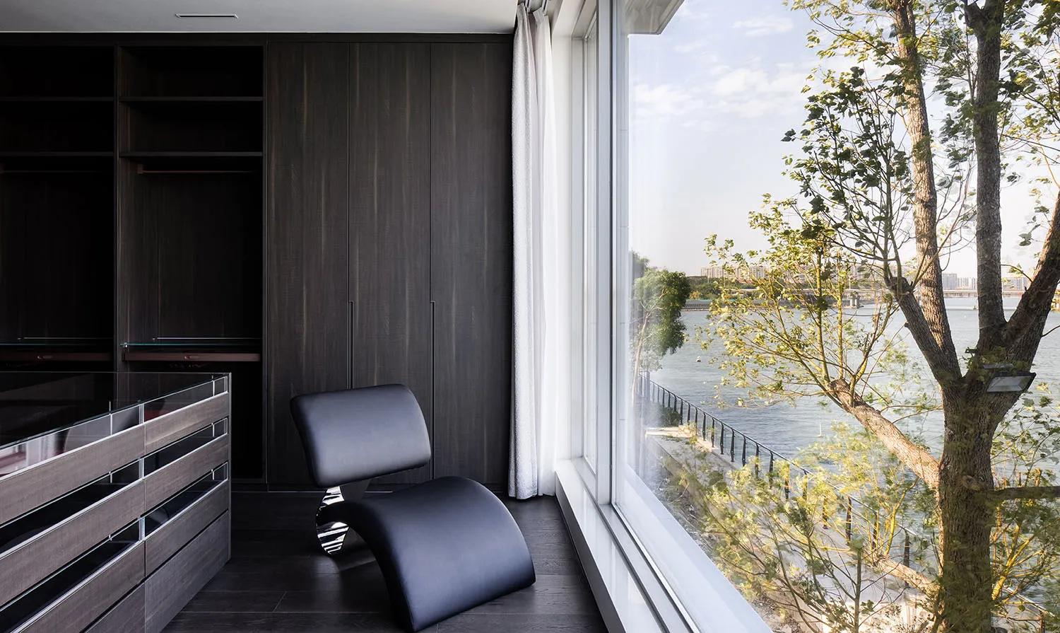 Modern living room featuring a sleek, black leather chair by the window.