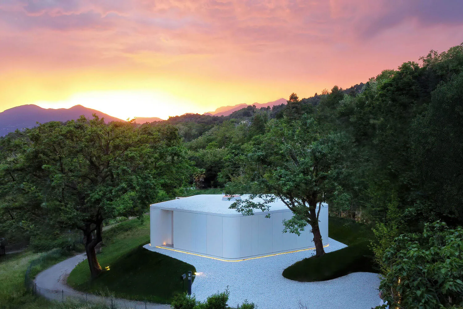 A minimalist residential architecture featuring clean lines and a concrete exterior at sunset.