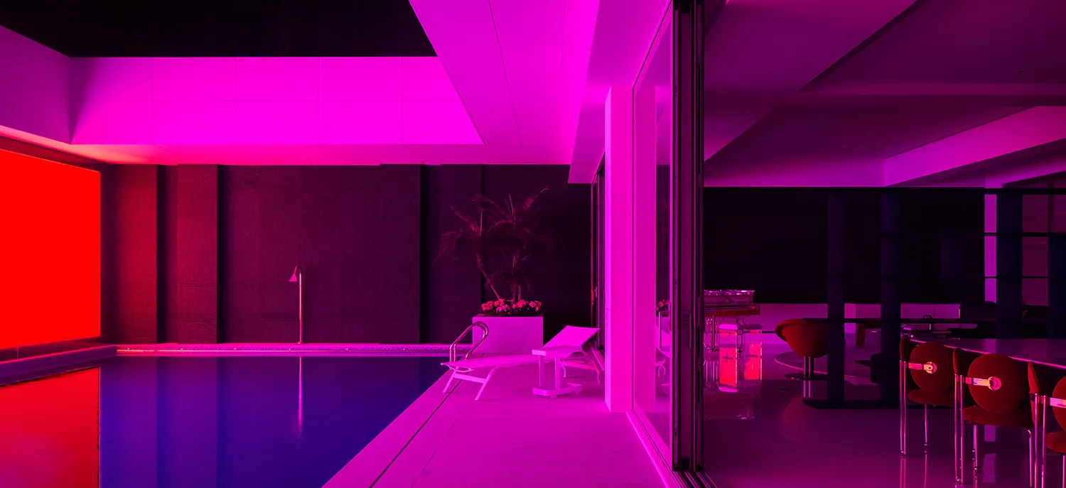 A modern interior space featuring a pool-side deck illuminated by vibrant purple lighting.