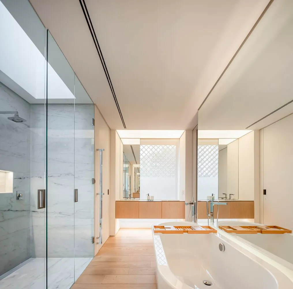 Modern minimalist bathroom with marble walls, wood accents, and a large glass shower.
