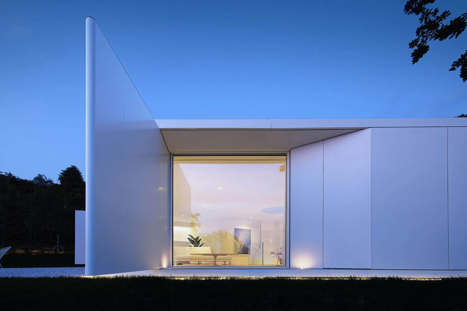 Modern minimalist exterior of a sleek metallic-clad building at dusk.
