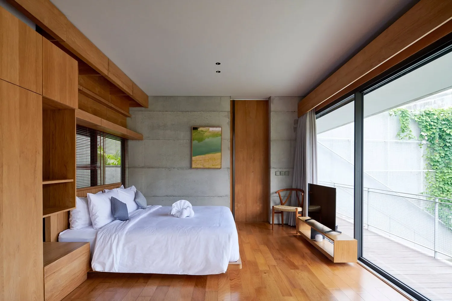 Modern bedroom with concrete accent wall and wooden flooring.