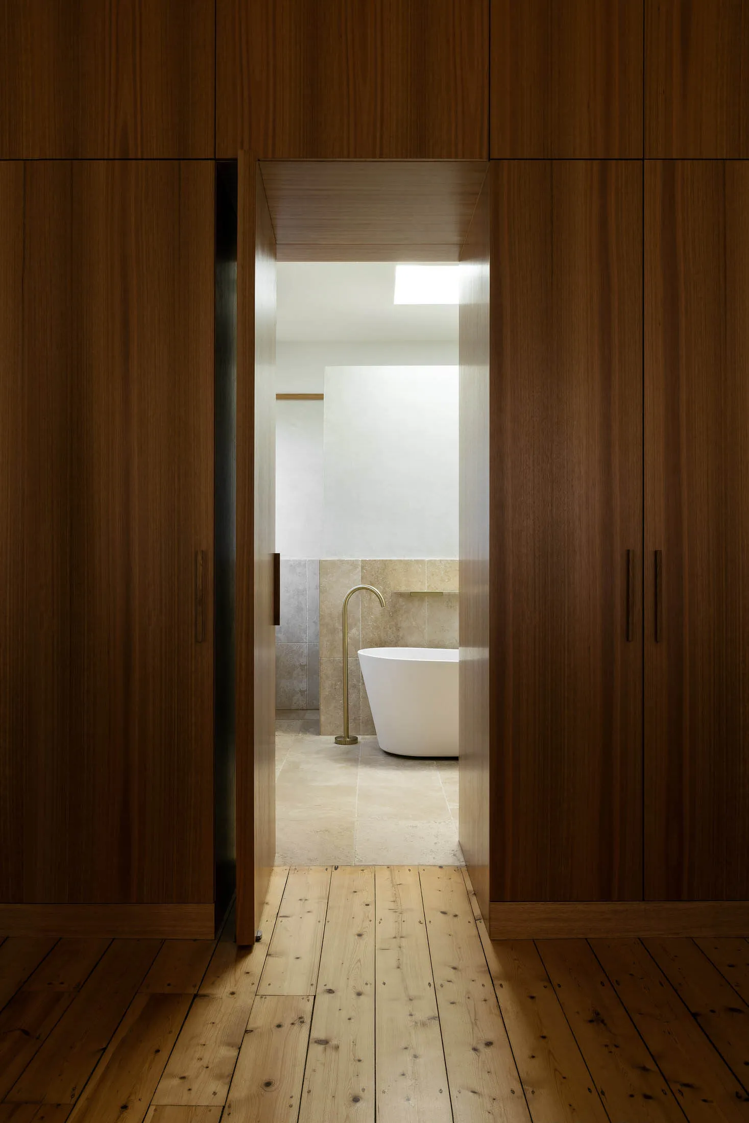 Modern bathroom with a white freestanding bathtub, tiled floor, and a brass faucet.