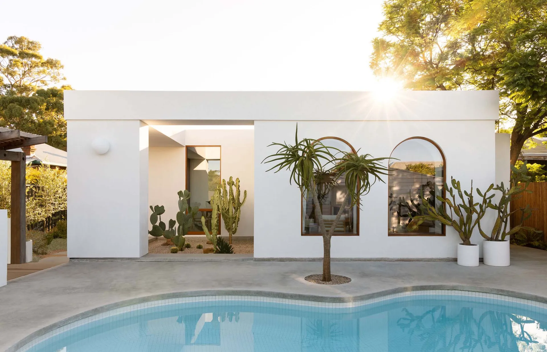 Modern, minimalist house with a concrete exterior and poolside view.