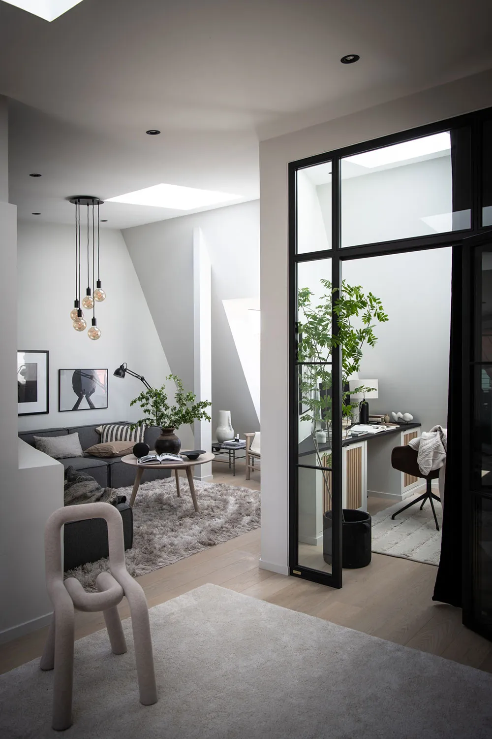 A modern living room with a sofa, coffee table, and a workspace with a desk and chair.