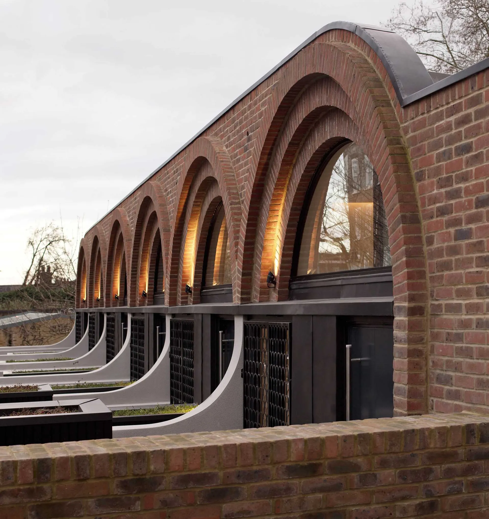 A modern architectural building with brick exterior featuring large arched windows.