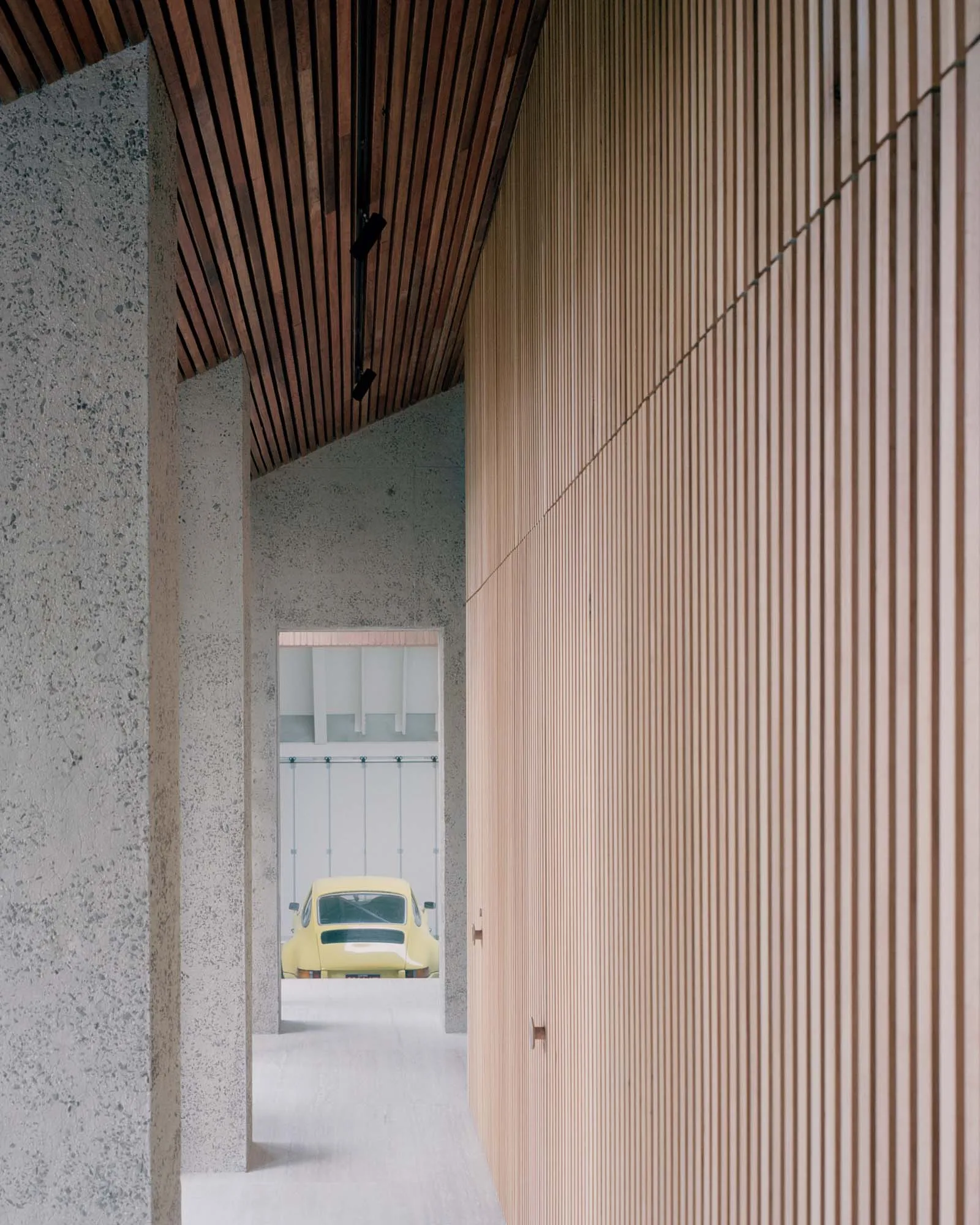 A modern interior design featuring concrete walls and wooden slat ceiling.
