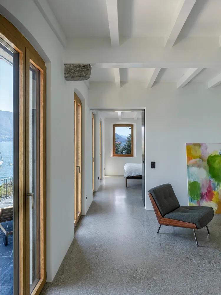 A modern minimalist bedroom featuring minimalist furniture on concrete floor, overlooking mountains.