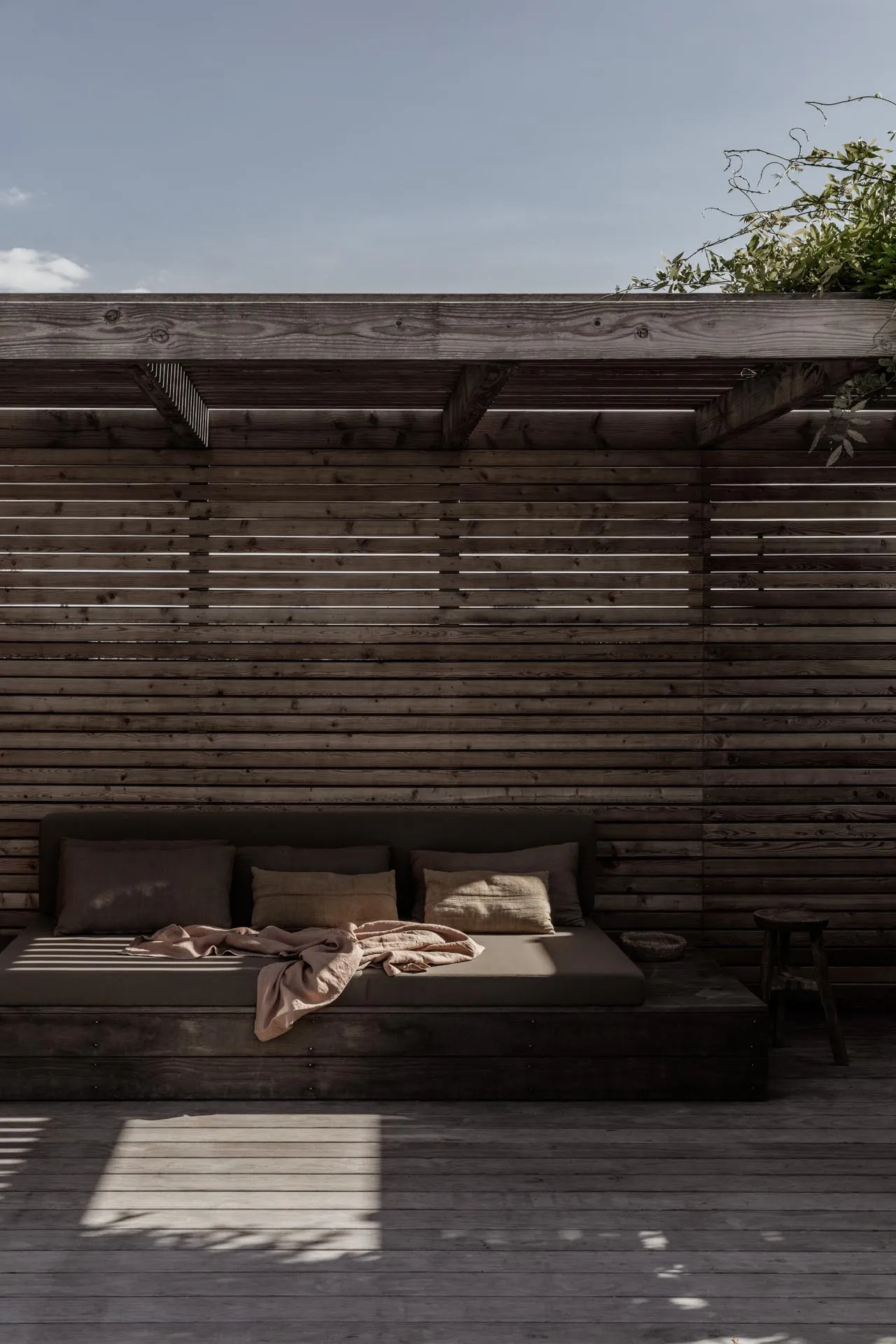 A modern outdoor space featuring a wooden lounger against a wooden wall and floor.