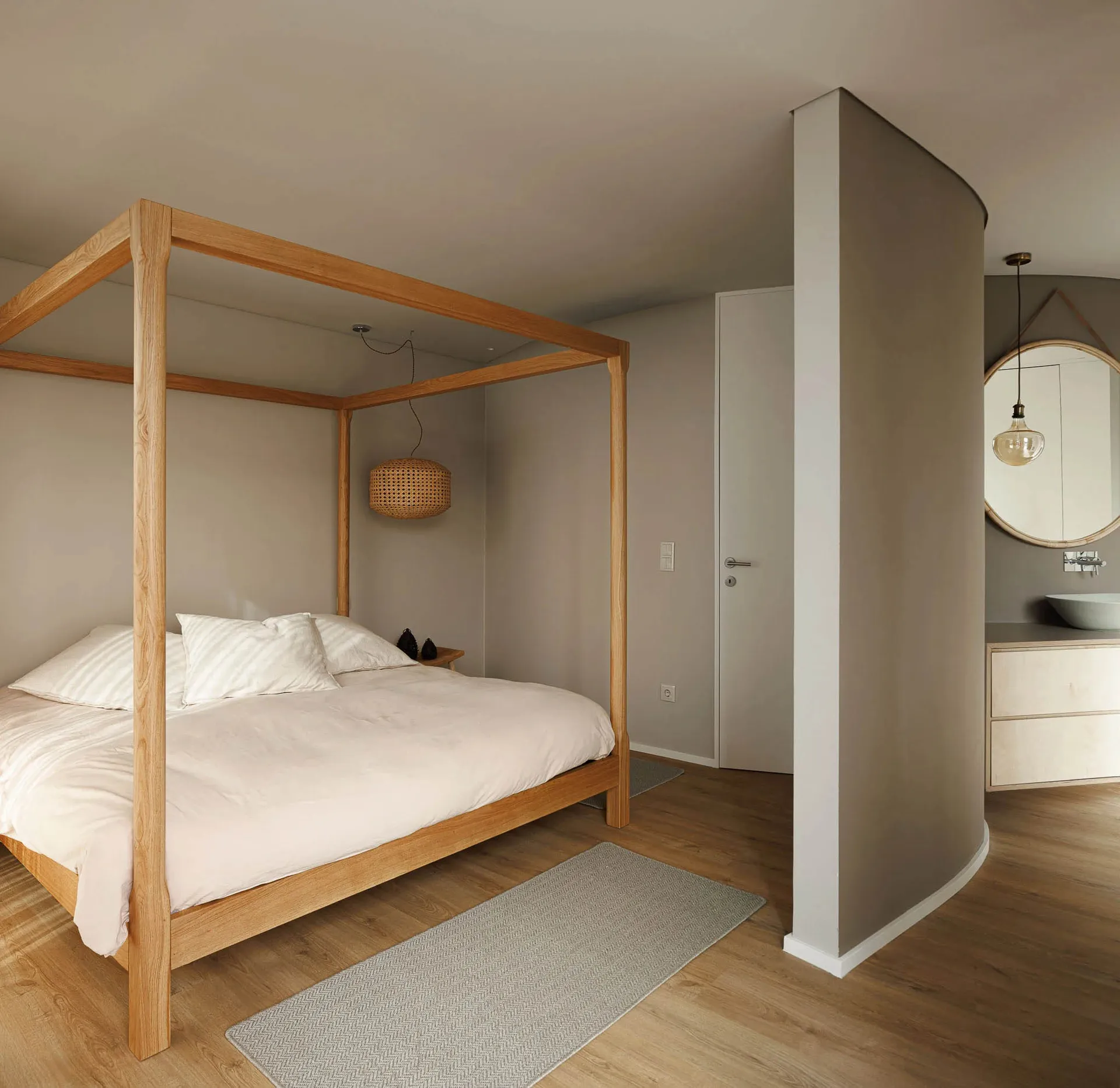 Minimalist bedroom with a wooden bed frame, rounded corner column, and grey flooring