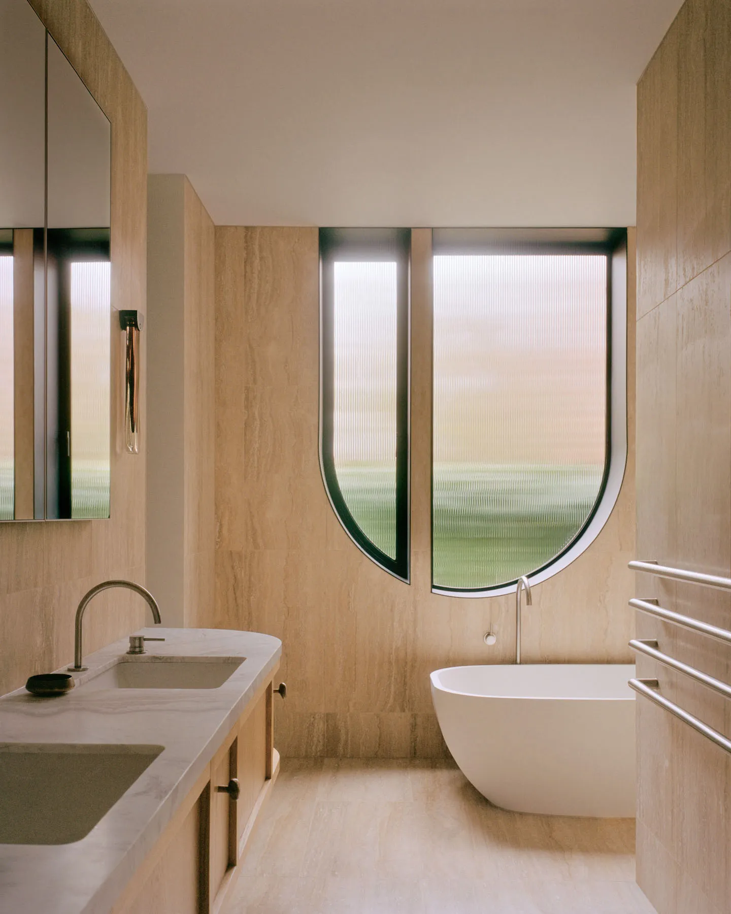 A modern bathroom with marble finishes and a freestanding bathtub.