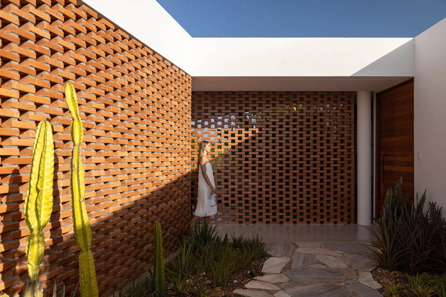A modern entranceway featuring a brick wall and a wooden lattice gate.