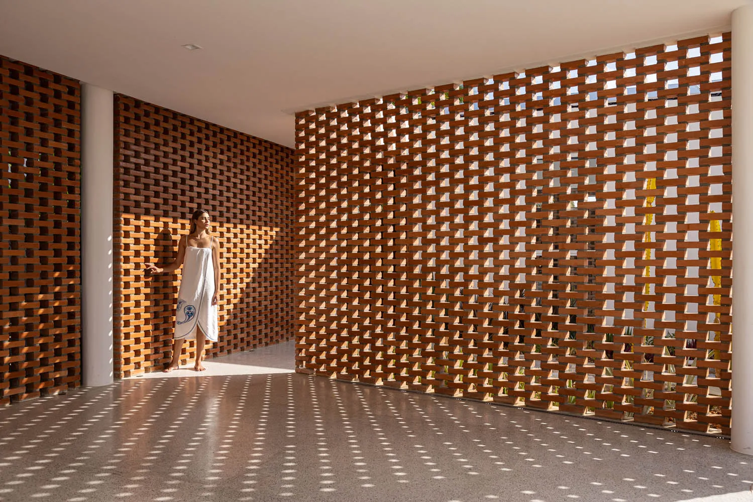 A woman standing in a room with modern interior design featuring brick walls.