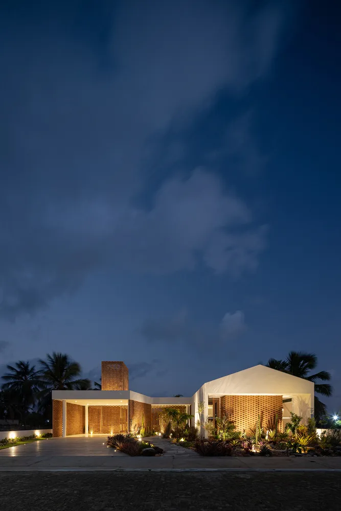 A modern entryway illuminated at night with wooden accents, cement flooring, and strategic lighting.