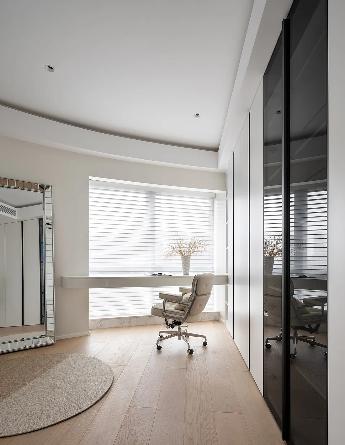 A modern minimalist home office featuring a white marble desk and chair, with sleek white furniture and natural light streami