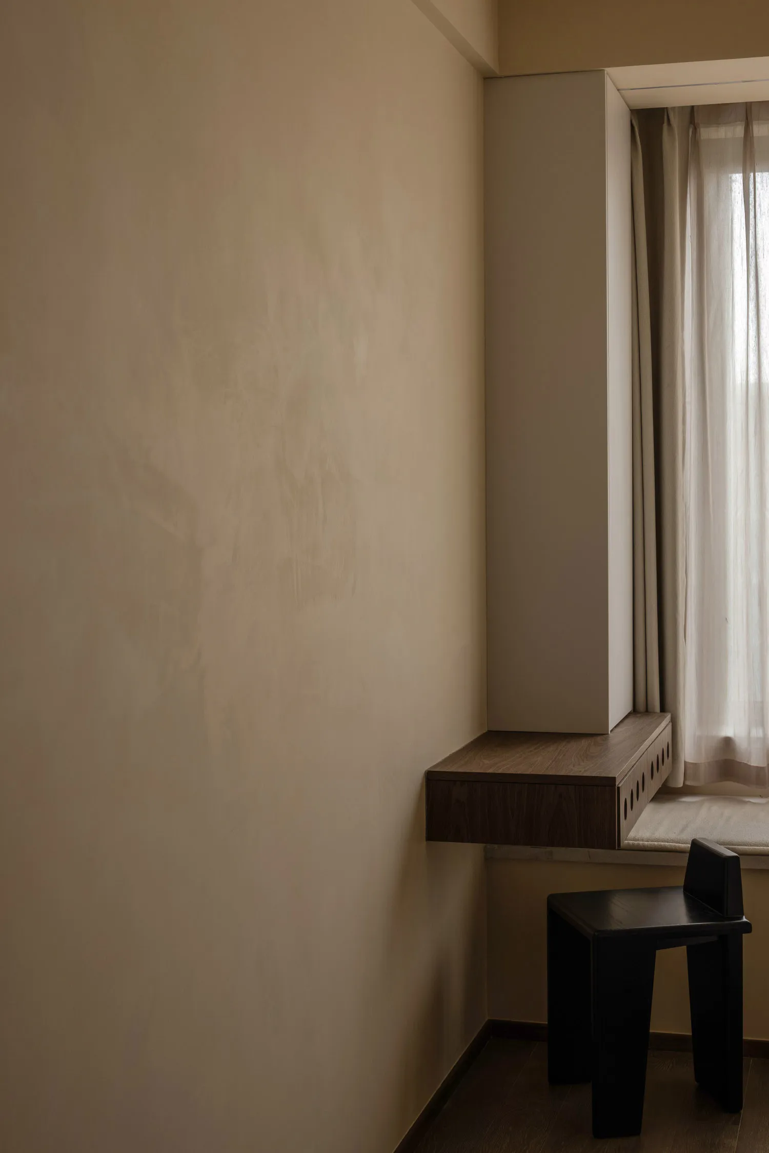 A minimalist home office space featuring a dark wood-paneled wall with a modern, sleek desk.