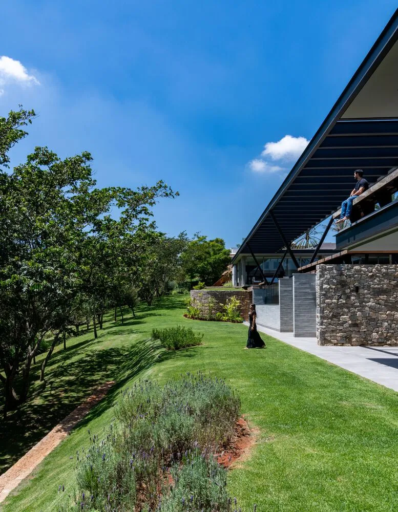 A modern residential exterior featuring a combination of concrete, grass, and wooden elements.