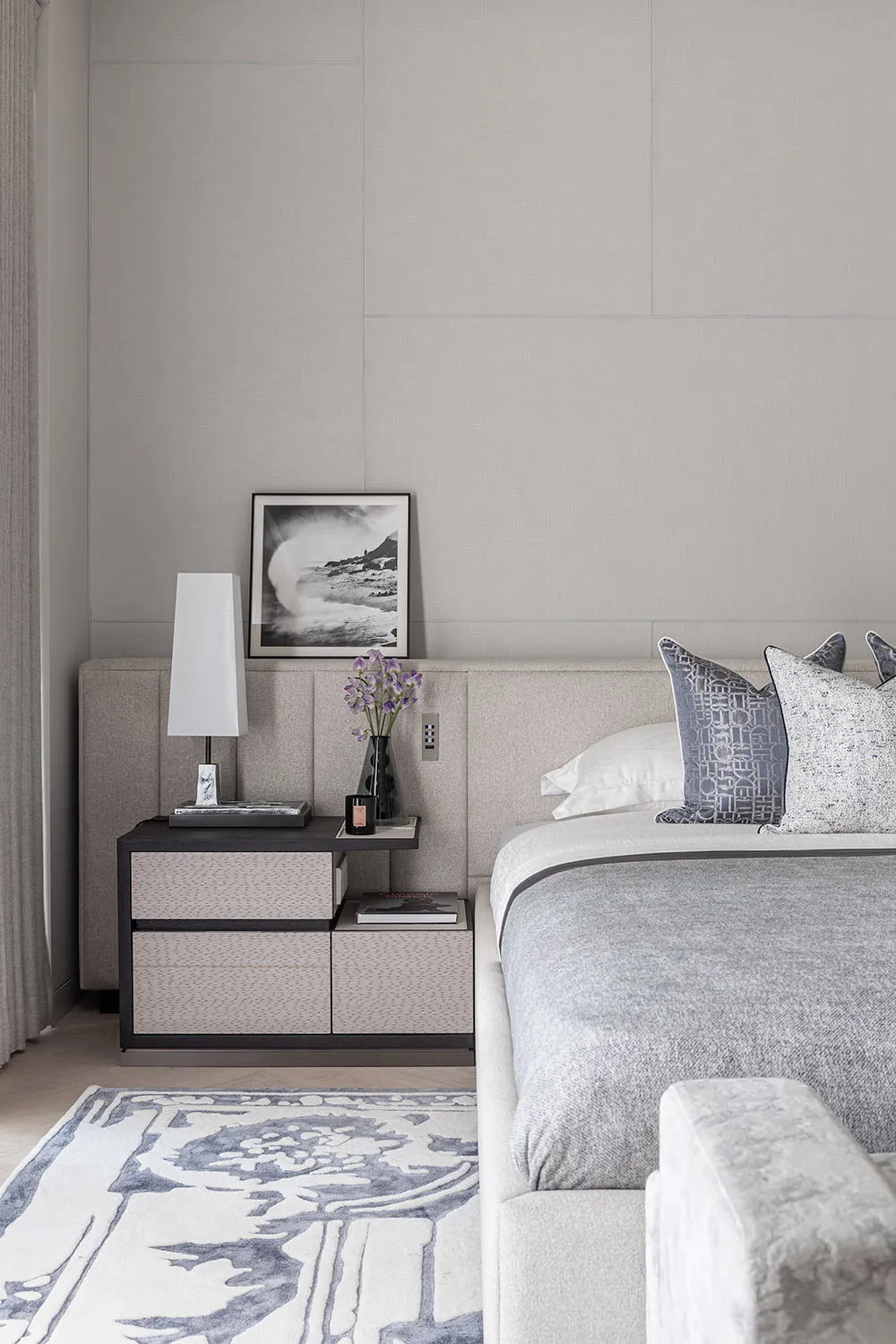 A modern minimalist bedroom featuring a bed with a fabric headboard and wooden nightstand.