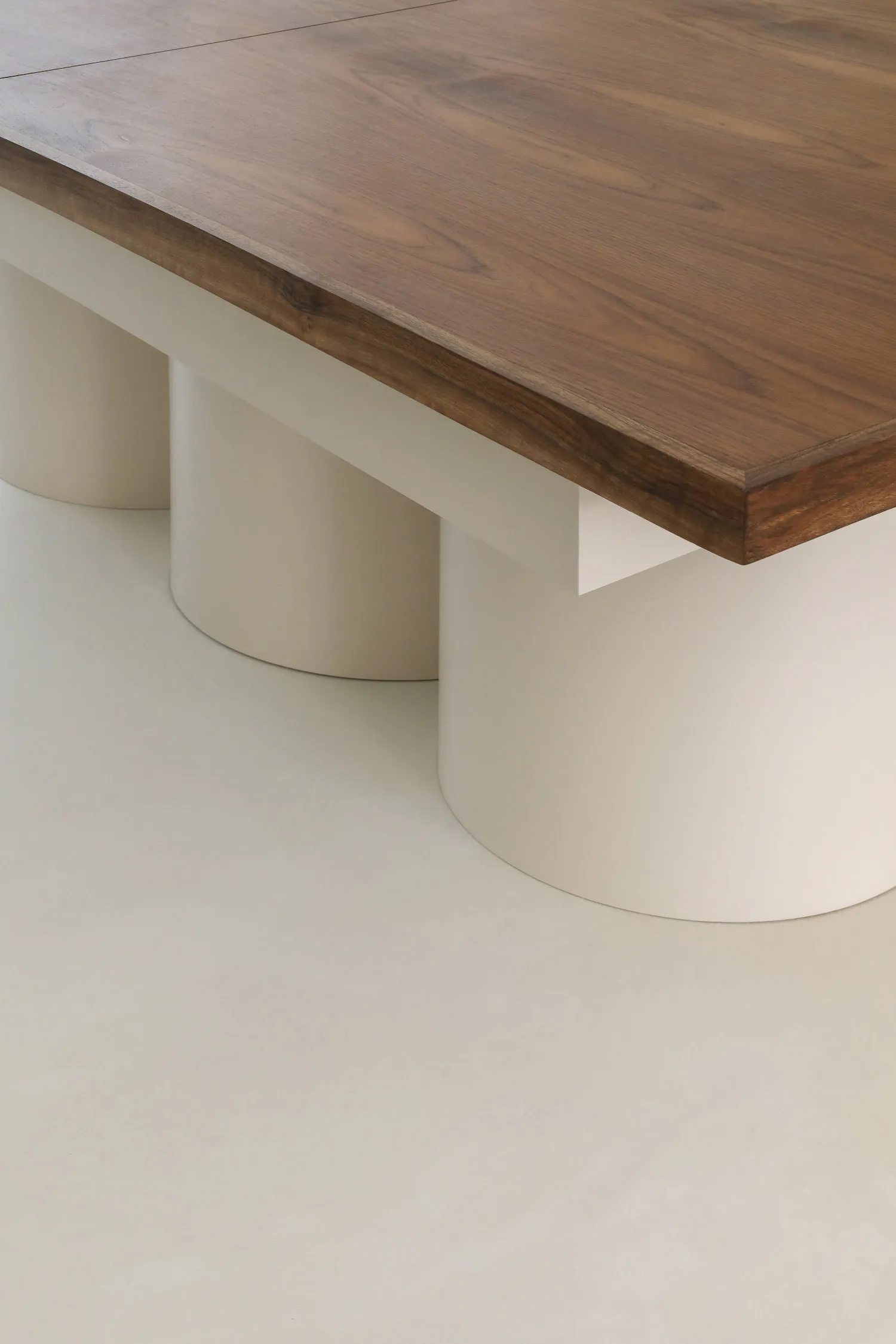 A minimalist table with a wooden top and white cylindrical bases.